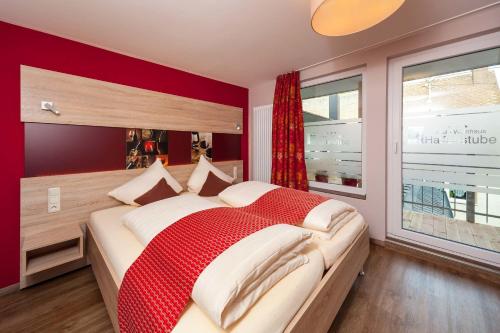 a bedroom with a large bed with a red wall at Hotel Halfenstube & Villa Spa 1894 in Senheim