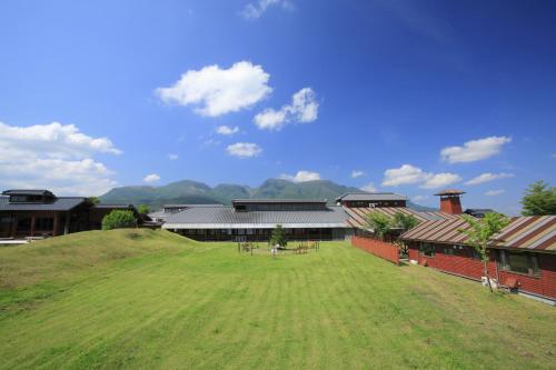 a building with a large grass field in front of it at Kuju Kogen Cottage in Taketa