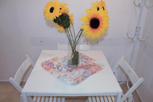 Una mesa blanca con un jarrón con flores. en Casa Vacanze Angelica, en Salerno