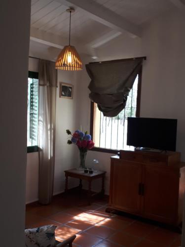 una sala de estar con TV y un jarrón de flores en Casa Paula en Las Rabonas