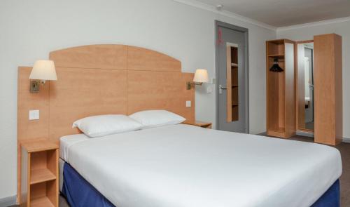 a hotel room with a bed and a dresser at Campanile Hotel Dartford in Dartford