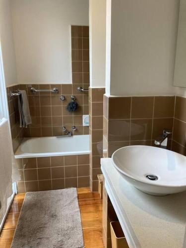a bathroom with a sink and a tub and a white sink at Fountain Villa in Camberwell