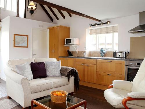 a living room with a couch and a kitchen at Stable Cottage in Icklesham