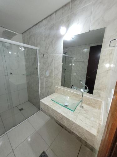 La salle de bains est pourvue d'une douche, d'un lavabo et d'un miroir. dans l'établissement Flat Completo Novo a 400m da praia com piscina, à São Vicente