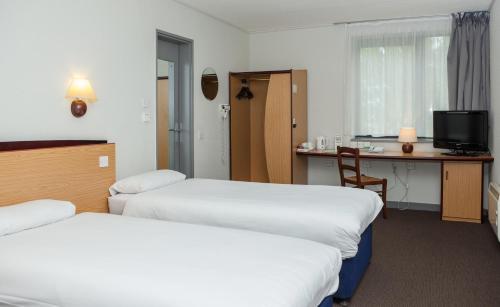 a hotel room with two beds and a desk at Campanile Hotel Dartford in Dartford