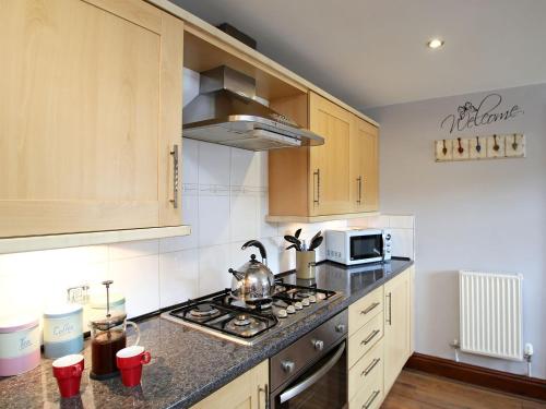 a kitchen with a stove and a microwave at 2 West Cottage in Blakeney