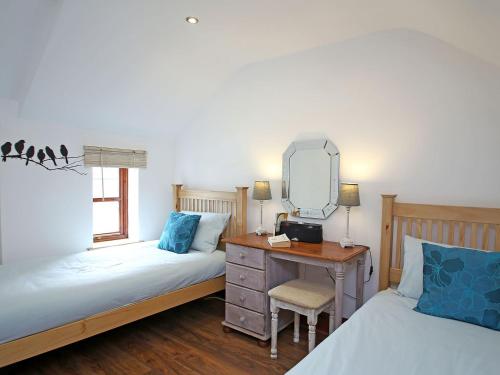 a bedroom with two beds and a desk with a mirror at 2 West Cottage in Blakeney
