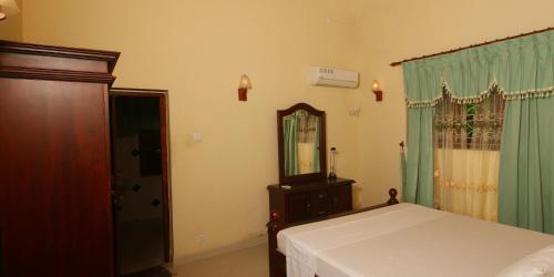a bedroom with a bed and a dresser and a mirror at Anna Apartments in Hikkaduwa