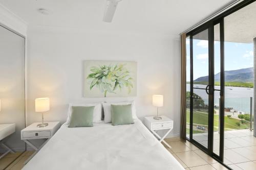 a white bedroom with a large bed with two lamps at Seascape in Cairns