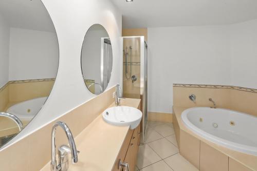 La salle de bains est pourvue d'un lavabo, d'une baignoire et d'un miroir. dans l'établissement Seascape, à Cairns