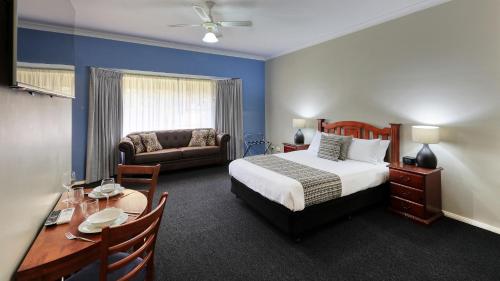 1 dormitorio con cama, mesa y sofá en Castlereagh Lodge Motel, en Coonamble