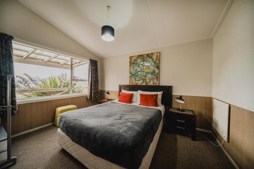 1 dormitorio con 1 cama con almohadas de color naranja y ventana en Lakes Edge Holiday Park, en Lake Tekapo