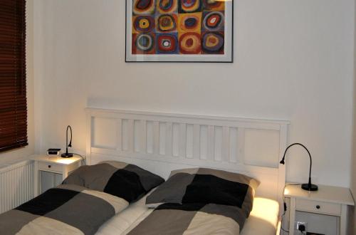 a bedroom with two beds and two lamps and a painting at Adoreo Apartments & Suites in Leipzig