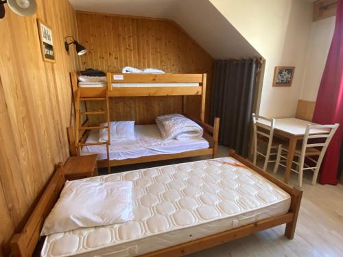 une chambre avec deux lits superposés et une table dans l'établissement Appartement familial de 3 pièces, au cœur du village, proche des pistes, idéal pour enfants - FR-1-515-126, à Villard-de-Lans