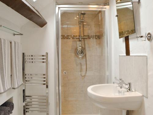 een witte badkamer met een douche en een wastafel bij Lower Barn in Wistanstow