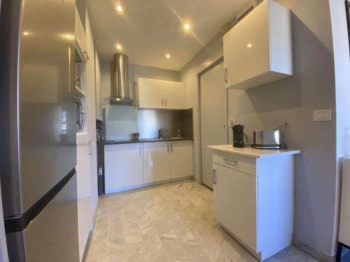 Elle comprend une petite cuisine avec des placards blancs et un réfrigérateur. dans l'établissement Sainte-Maxime: Appartement 2 pièces rénové avec terrasse, climatisation et à 2 pas de la plage - FR-1-226-498, à Sainte-Maxime