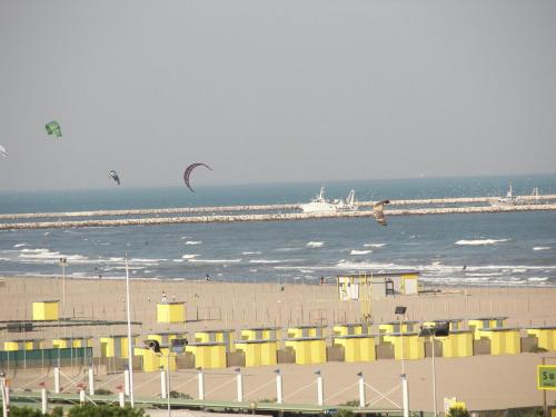 a beach with people flying kites in the ocean at Hotel Bristol in Sottomarina