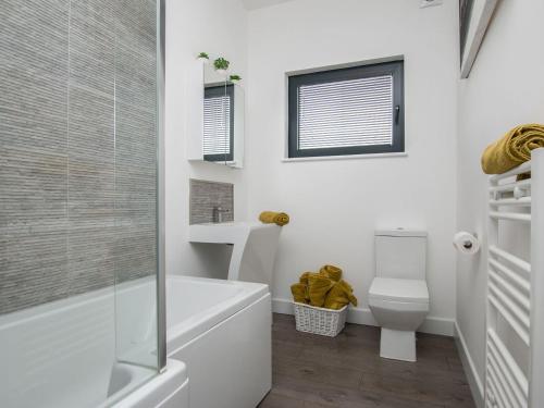 een witte badkamer met een bad en een toilet bij Sunnyside Lodge in Glastonbury