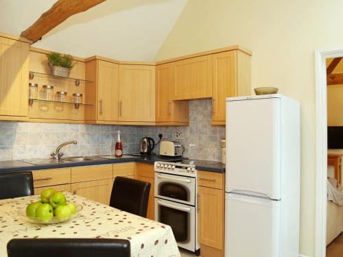 a kitchen with wooden cabinets and a white refrigerator at Tilmangate Barn in Ulcombe