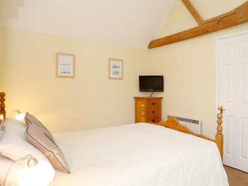 a bedroom with a white bed and a tv at Tilmangate Barn in Ulcombe