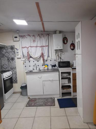 cocina con armarios blancos, fregadero y ventana en Cabaña El Quijote, en Valdivia