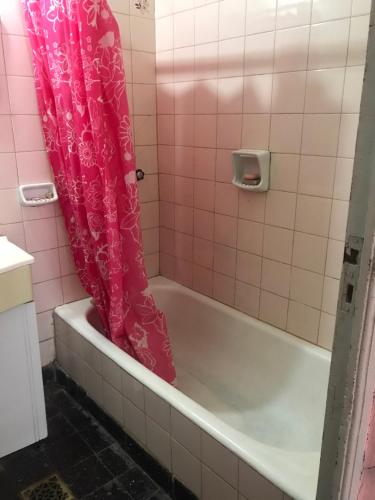 a bathroom with a tub with a pink shower curtain at Chandra in Gualeguaychú