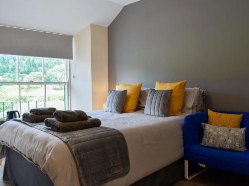 a bedroom with a large bed and a blue chair at Court House Mews - Uk11119 in Torver