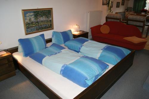 a large bed with blue pillows and a red couch at Gästehaus Ferienwohnungen LACKNER in Rennweg