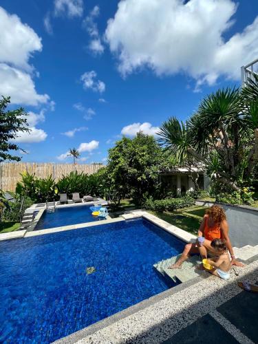 una donna e un bambino seduti accanto alla piscina di Private suite in a kids friendly big shared villa in Canggu a Canggu