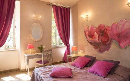 a bedroom with a bed with pink pillows on it at Hostellerie du Cigalou - Teritoria in Bormes-les-Mimosas