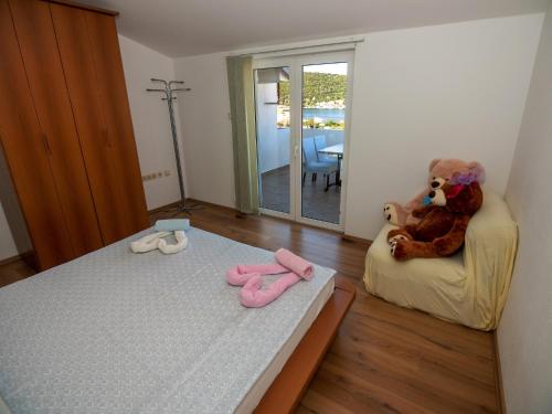 ein Schlafzimmer mit einem Bett, einem Teddybär und rosa Hausschuhen in der Unterkunft Apartments Suzy - 80m from the sea in Supetarska Draga