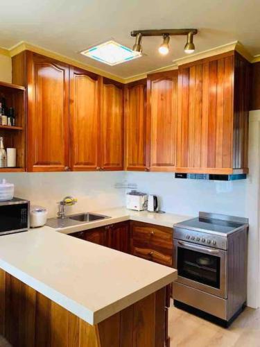 a kitchen with wooden cabinets and a stove top oven at Rose Homey Home in Glenorchy