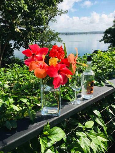 a table with a vase of flowers and two wine glasses at Aore Hibiscus Retreat in Aimbuei Bay