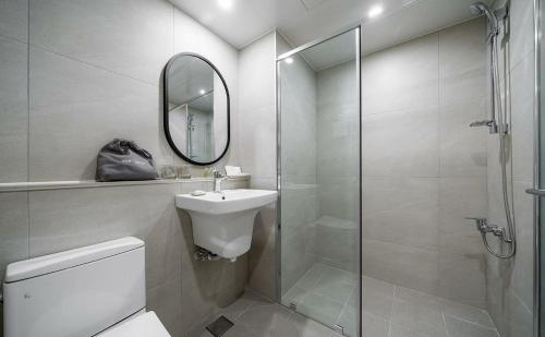a bathroom with a toilet and a sink and a shower at Geoje Mongdol Beach H Avenue Hotel in Geoje 