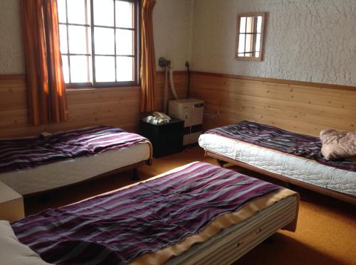 a room with three beds in it with windows at Pension Starlight Azumi in Hakuba