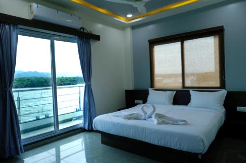a bedroom with a bed with two white towels on it at Sai Unity Boutique Stay in Garudeshwar