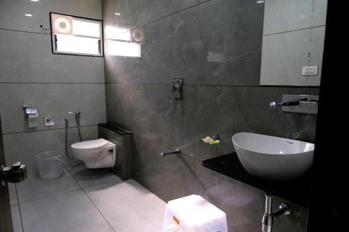 La salle de bains est pourvue d'un lavabo, de toilettes et d'un miroir. dans l'établissement Hotel Sai Unity Room, à Garudeshwar