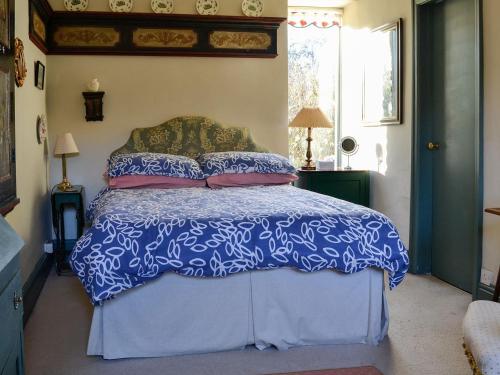 a bedroom with a blue and white bed with pillows at Riverside Lodge in Wyck Rissington