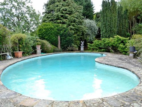 a large pool with blue water in a garden at Riverside Lodge in Wyck Rissington
