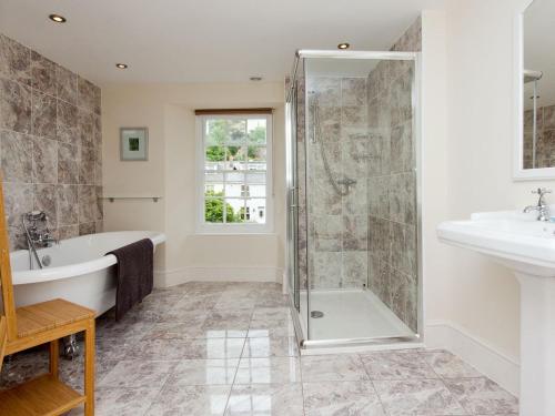 a bathroom with a shower and a tub and a sink at Hawkins in Dartmouth