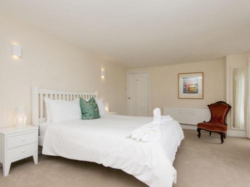 a white bedroom with a large white bed and a chair at Hawkins in Dartmouth