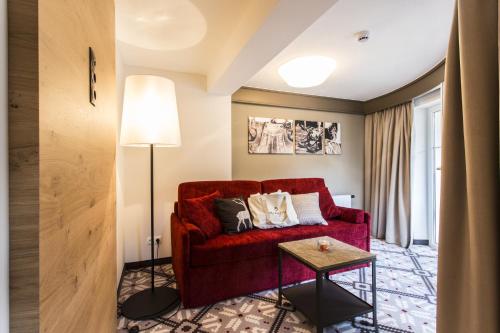 Una sala de estar con un sofá rojo y una mesa. en Hotel Valentin, en Sölden