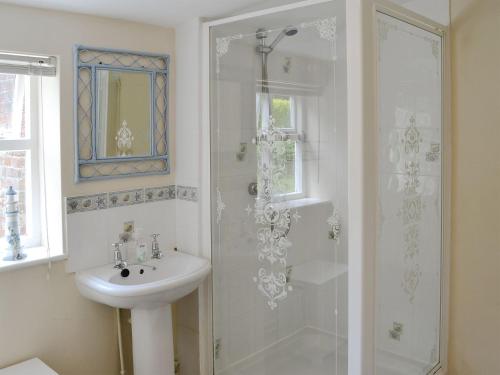 a white bathroom with a sink and a shower at Forge Cottage in Happisburgh