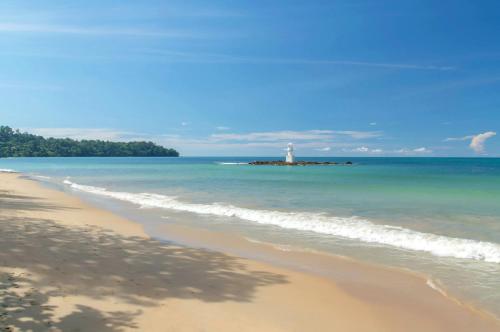 a beach with a light house in the ocean at The Leaf Oceanside by Katathani - SHA Extra Plus in Khao Lak