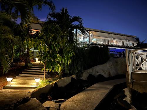a house with stairs and palm trees at night at GREEN LORD DOMAINE - Lodges Piscine & Spa - Bar & Lounge - Restaurant gastronomique in Lamentin