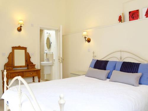 a bedroom with a large white bed with blue pillows at The Bothy At Fordcombe in Speldhurst