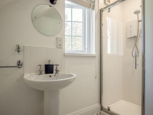 a white bathroom with a sink and a shower at Summerhill Cottage HW7101 in Amroth
