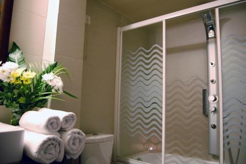a bathroom with a shower with towels on a toilet at Paris Hotel in Xanthi
