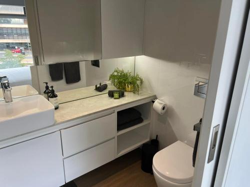 a white bathroom with a sink and a toilet at Centrepoint Units Heidelberg in Melbourne