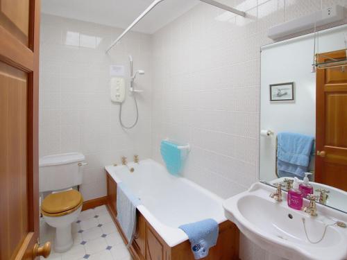 uma casa de banho com uma banheira, um WC e um lavatório. em Conheath Gatelodge Cottage em Kingholm Quay